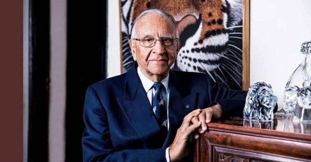 "Dr. M. K. Ranjitsinh, pioneer of wildlife conservation in India, standing in front of a tiger portrait"